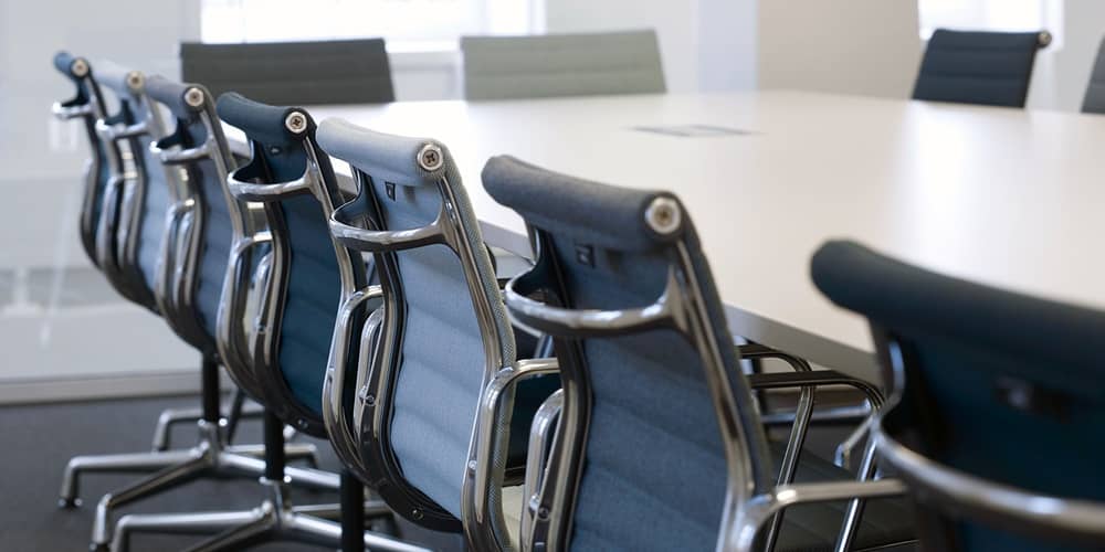 Mehrere gleiche Konferenzstuhl-Modelle in unterschiedlichen Farben stehen an einem Sitzungstisch